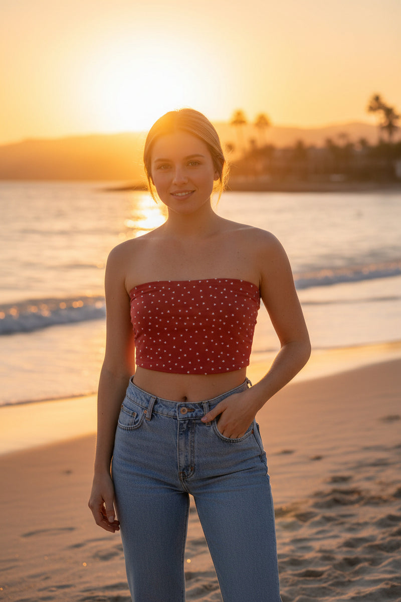 Person wearing a strapless polka dot top and blue jeans on a plain background