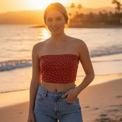 Person wearing a strapless polka dot top and blue jeans on a plain background