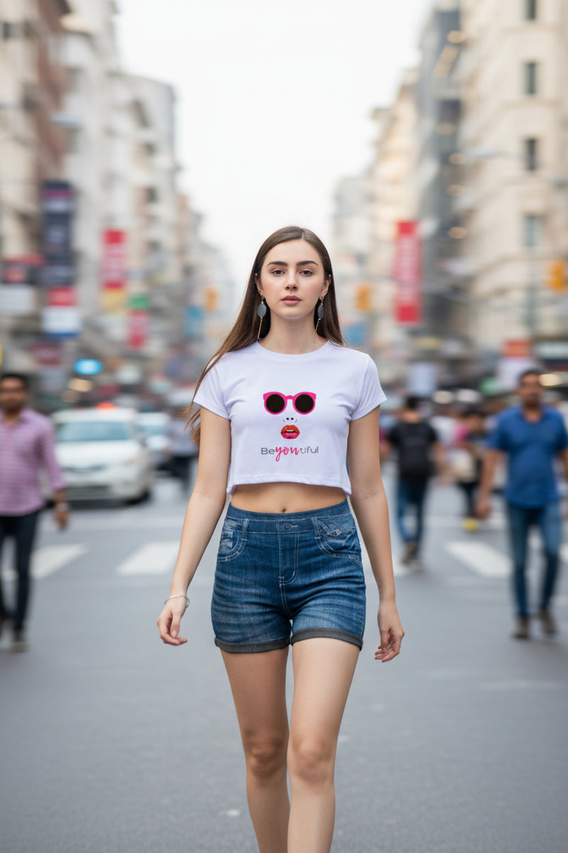 Woman wearing a light purple t-shirt with sunglasses and lipstick graphic, and blue denim shorts on a white background.