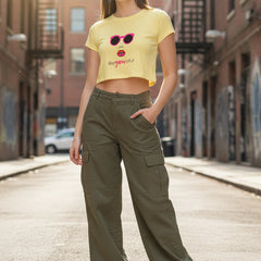 Woman wearing a yellow crop top with sunglasses and lipstick graphic and denim shorts on a white background