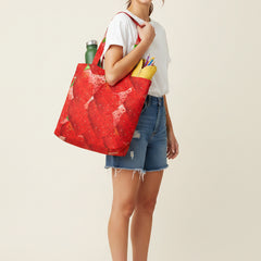 Tote bag with strawberry pattern filled with groceries on a white background