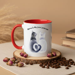 Two mugs with red handles on a pink background, one featuring a cat illustration and text.