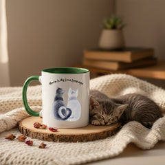 Two mugs with green handles on a pink background, one featuring a cat illustration and text.