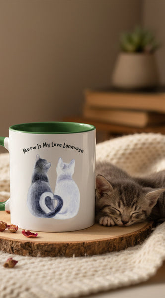 Two mugs with green handles on a pink background, one featuring a cat illustration and text.
