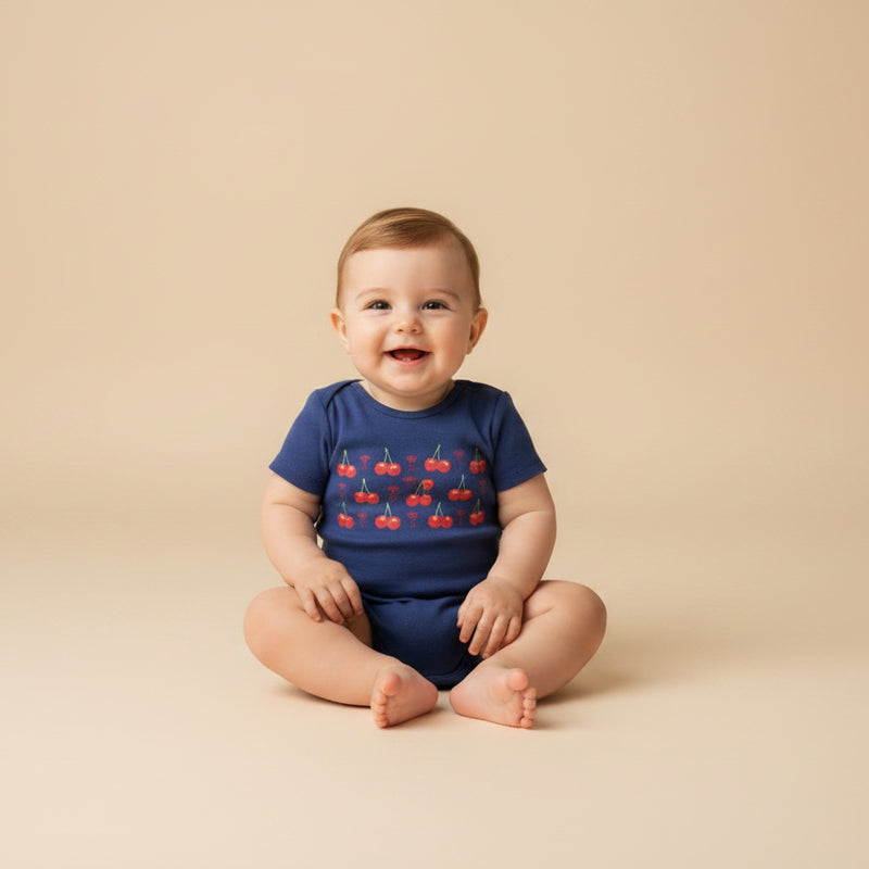 Navy blue baby onesie with red cherry design and text on a white background
