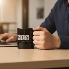 Two black mugs with periodic table elements spelling 'Coffee' on a beige background with colorful candies.