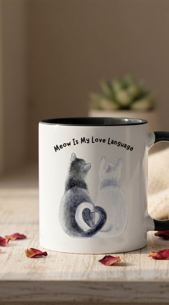 Two mugs with black handles on a pink background, one featuring a cat illustration and text.