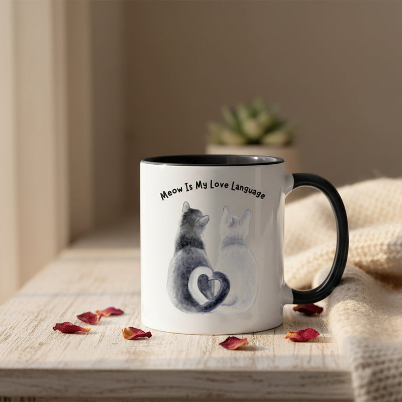 Two mugs with black handles on a pink background, one featuring a cat illustration and text.