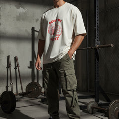 Beige t-shirt with red graphic and text on a light gray background
