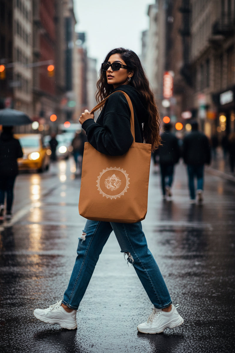 Brown tote bag with a white design held by a person against a gray background