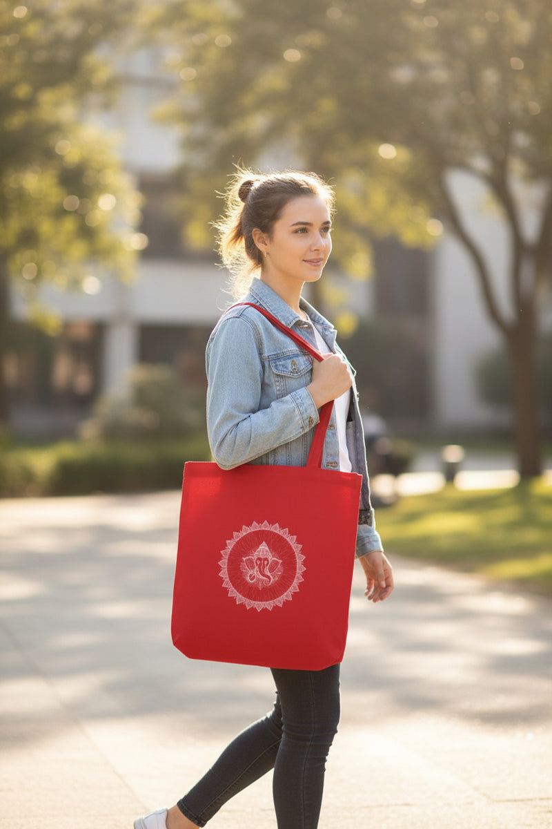 Red tote bag with white design held by a person against a gray wall