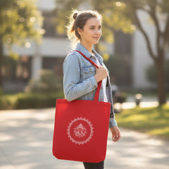 Red tote bag with white design held by a person against a gray wall