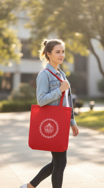 Red tote bag with white design held by a person against a gray wall