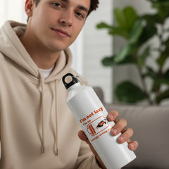 White water bottle with humorous design and text on a blurred green outdoor background