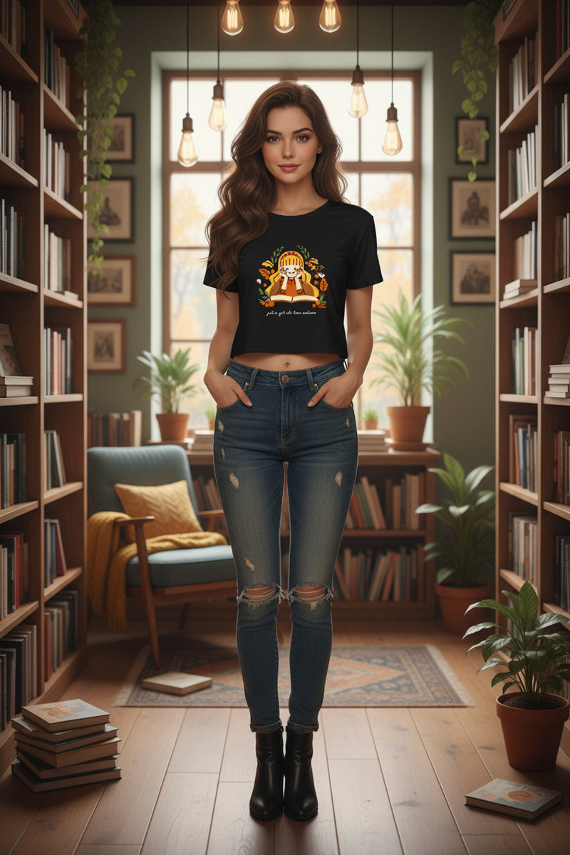 Black t-shirt with a graphic of a girl reading a book surrounded by nature elements on a white background.