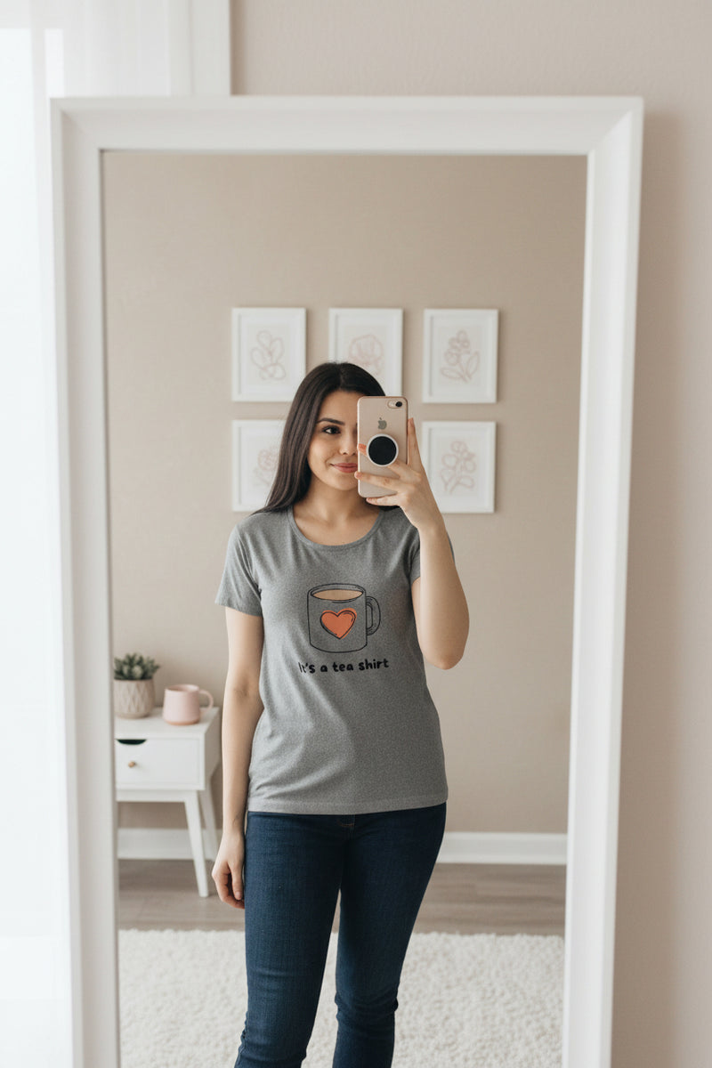 Woman wearing a gray t-shirt with a coffee mug graphic and text.