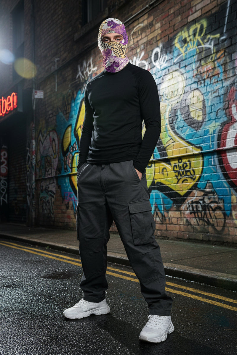 Person wearing a colorful balaclava with leopard print design on a white background