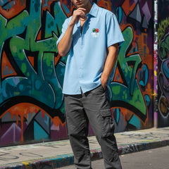Person wearing a light blue polo shirt with a logo, dark gray cargo pants, and white sneakers standing in front of a colorful graffiti wall.