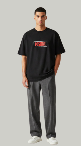 Man wearing a black t-shirt with a red and white logo and gray pants on a light gray background