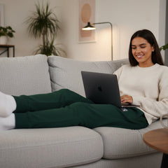 Woman using a laptop on a couch in a cozy living room.