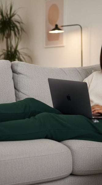Woman using a laptop on a couch in a cozy living room.