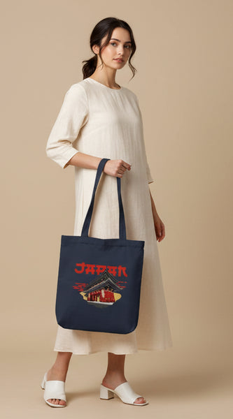 Navy tote bag with Japanese temple design and 'Japan' text held by a person against a gray background