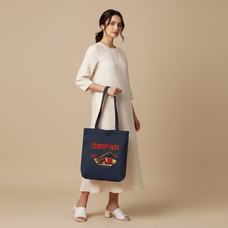 Navy tote bag with Japanese temple design and 'Japan' text held by a person against a gray background